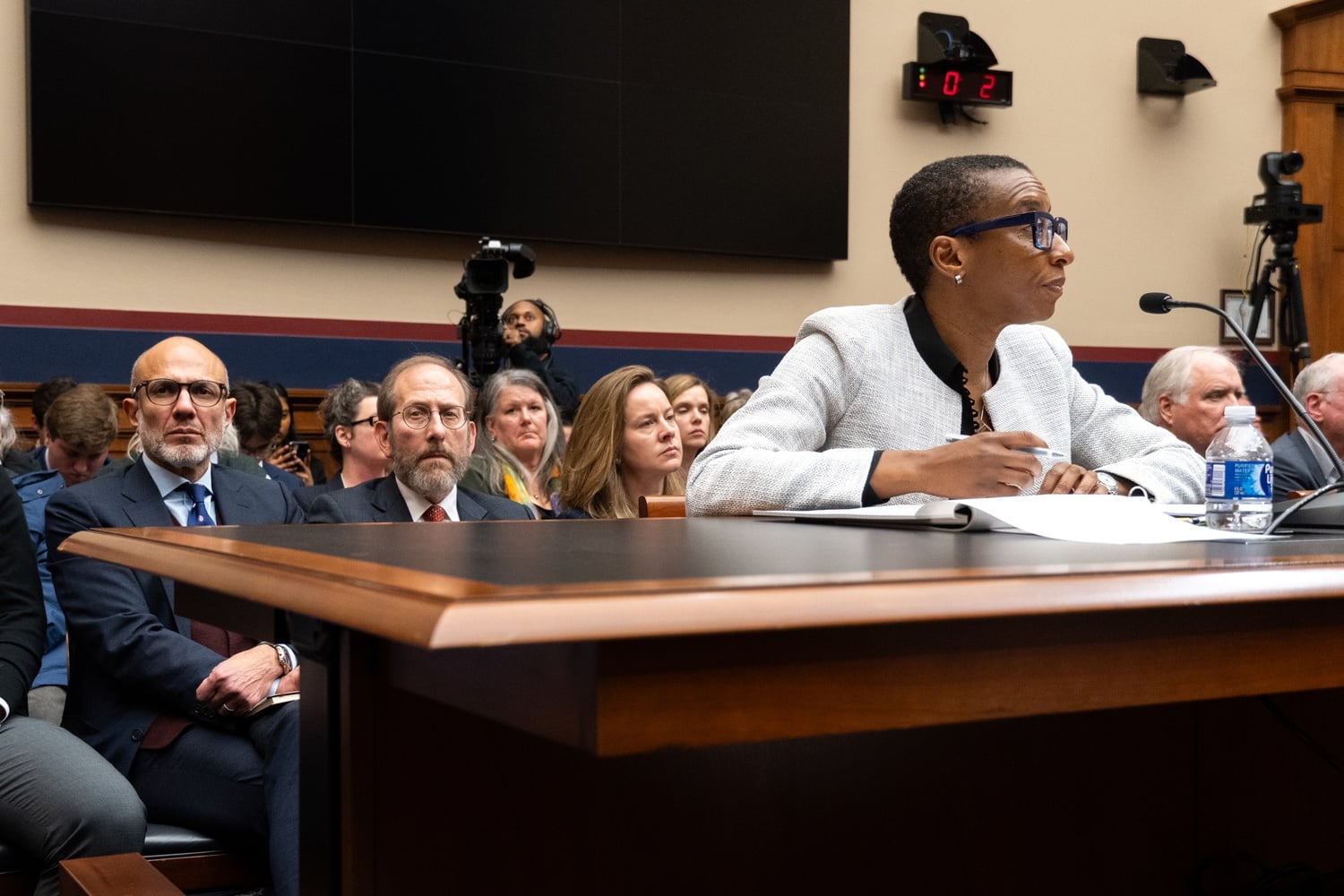 Longtime Harvard Provost Alan M. Garber '76, pictured behind Gay at the Dec. 5 congressional hearing, became the University's interim president after Gay resigned.