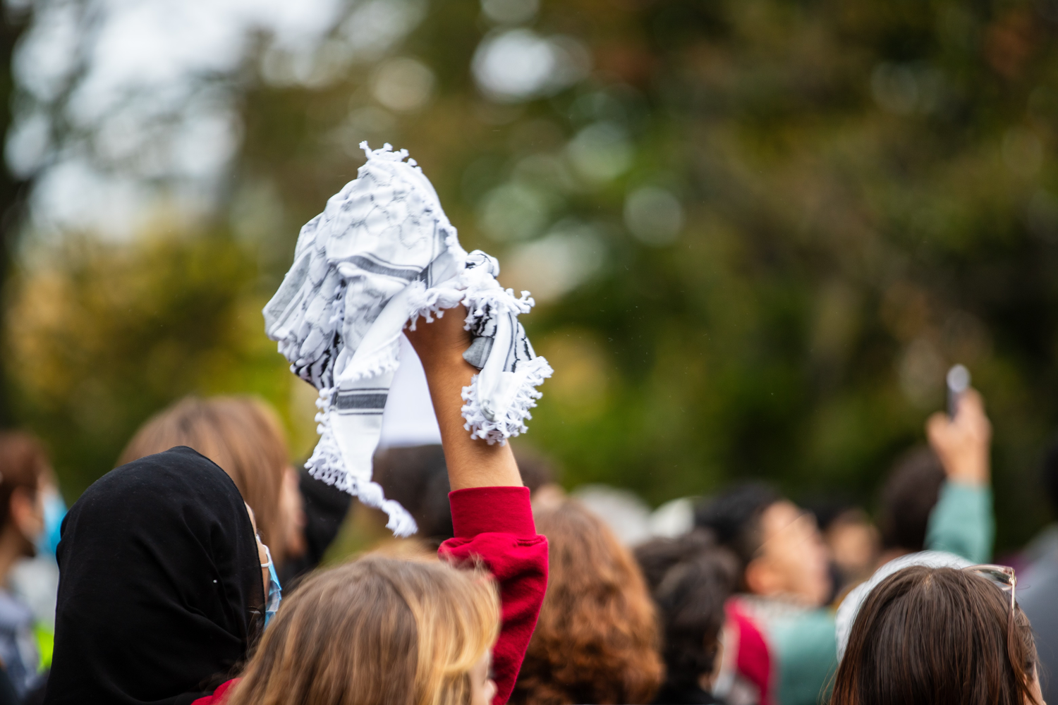 A student holds up a keffiyeh, a traditional Arab headdress, at a protest.