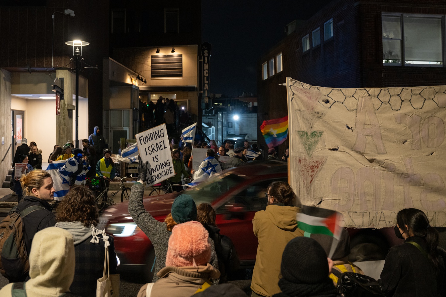 Sinclair staff members and Cambridge residents protest outside the concert venue, boycotting a concert in support of Israel by Israeli artist Ishay Ribo. Counter-protesters with Israeli flags face them across the street. Staff at The Sinclair boycotted a concert in support of Israel by Israeli artist Ishay Ribo and protested outside the venue Tuesday night.
