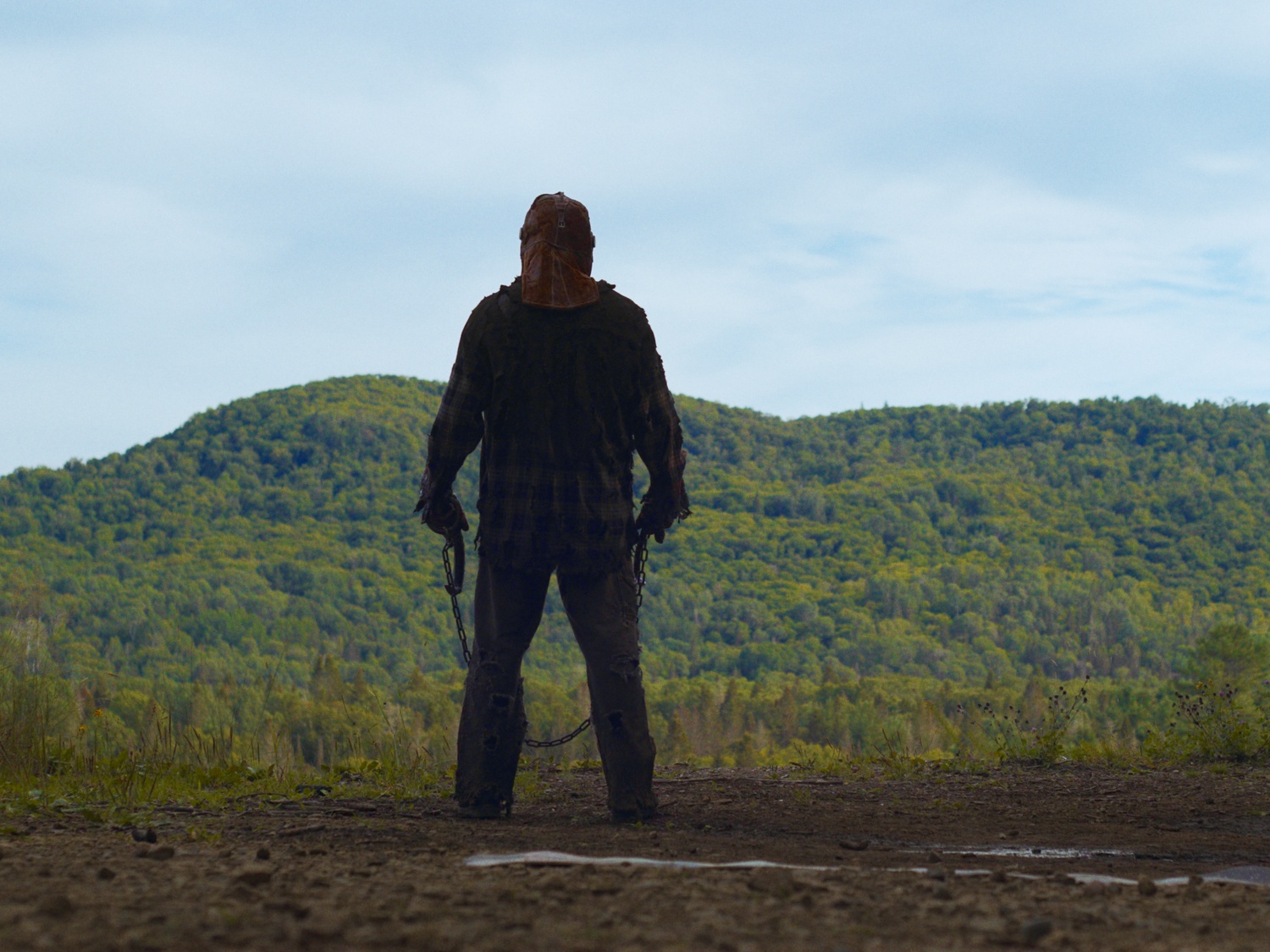 The faceless monster of "In a Violent Nature" stands threateningly in the distance.