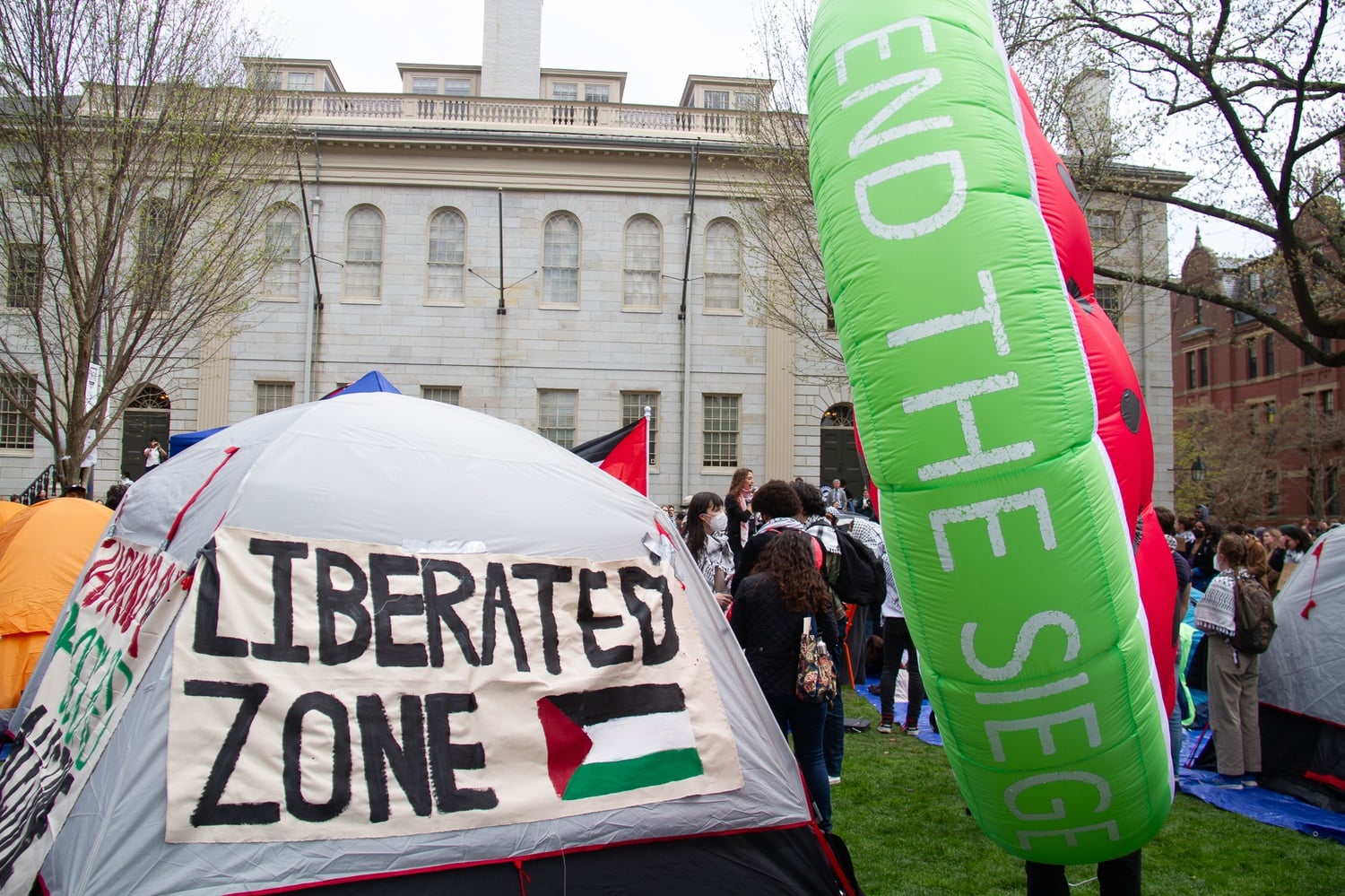 A sign advertising the "Liberated Zone" sits next to an inflatable watermelon bearing the slogan "End the Siege." The watermelon, which shares the same colors as the Palestinian flag, has emerged as a symbol of solidarity with Palestine.