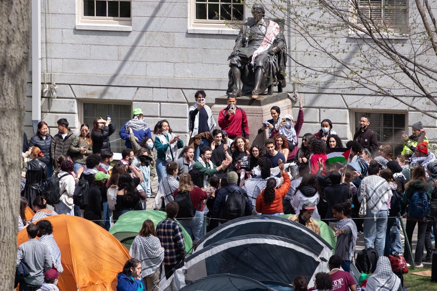 Pro-Palestine students sing and dance before the John Harvard Statue in Harvard Yard Wednesday afternoon.