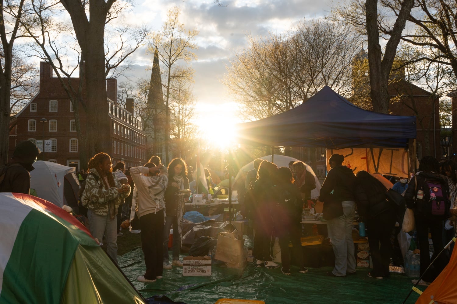 Members of the pro-Palestine encampment in Harvard Yard prepare to eat dinner as the sun sets.