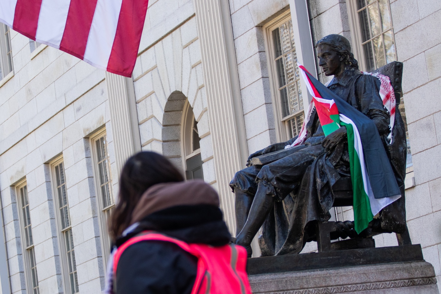 A Palestinian flag sits draped over the John Harvard Statue Thursday morning, in view of encampment members and onlookers.