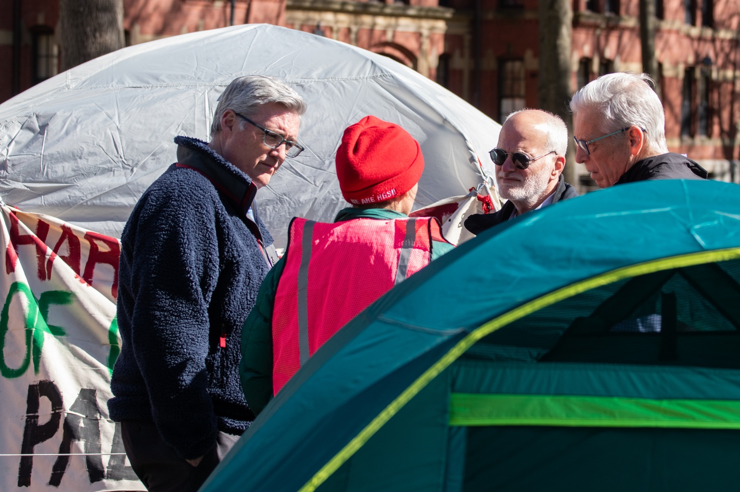 Harvard administrators, including Dean of Students Thomas Dunne, speak with a security marshal at the encampment Thursday afternoon. Dunne arrived at Harvard Yard Thursday afternoon and began checking and photographing participants' Harvard University IDs.