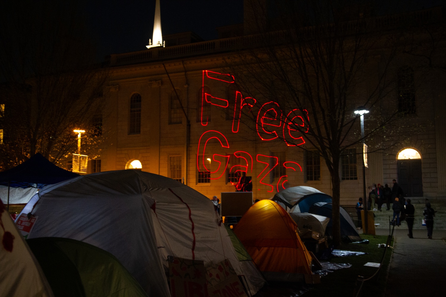 Protestors project red text reading 'Free Gaza' over University Hall and the John Harvard statue.