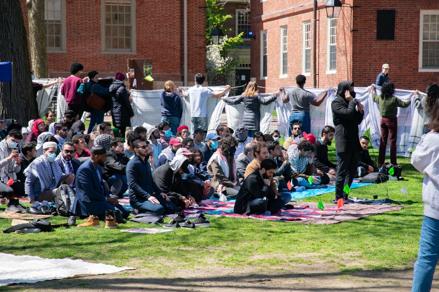 Protesters hold keffiyehs to obstruct passerby view of worshippers praying the jum'a, or Friday, prayer.