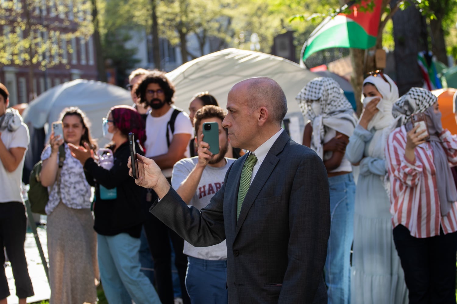 Dean of Student Services Michael Burke films the faces of student protesters on his mobile phone while walking around the Yard.