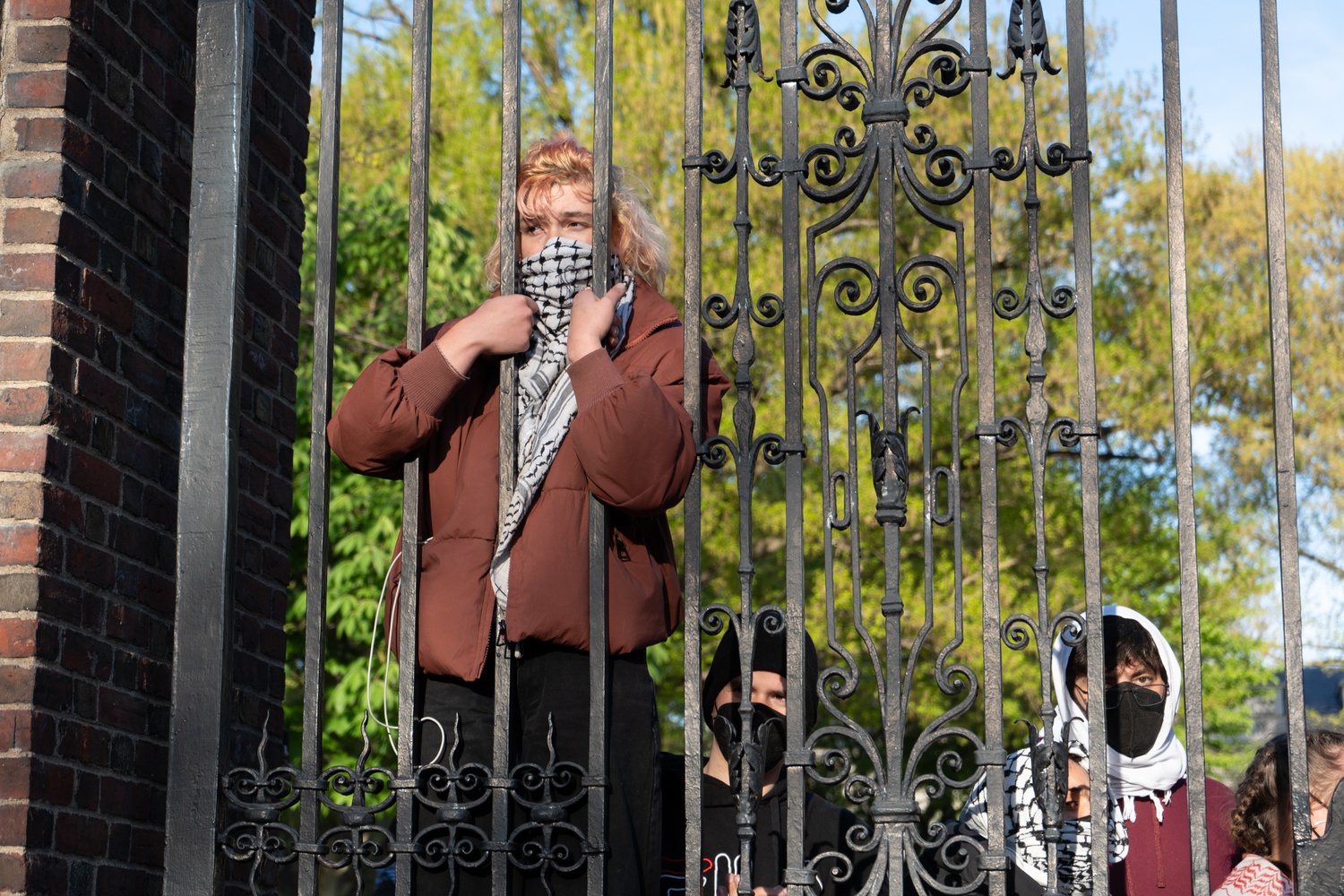 A pro-Palestine protester partially climbed Johnston Gate from within Harvard Yard to watch more than 200 people rally outside the Yard.