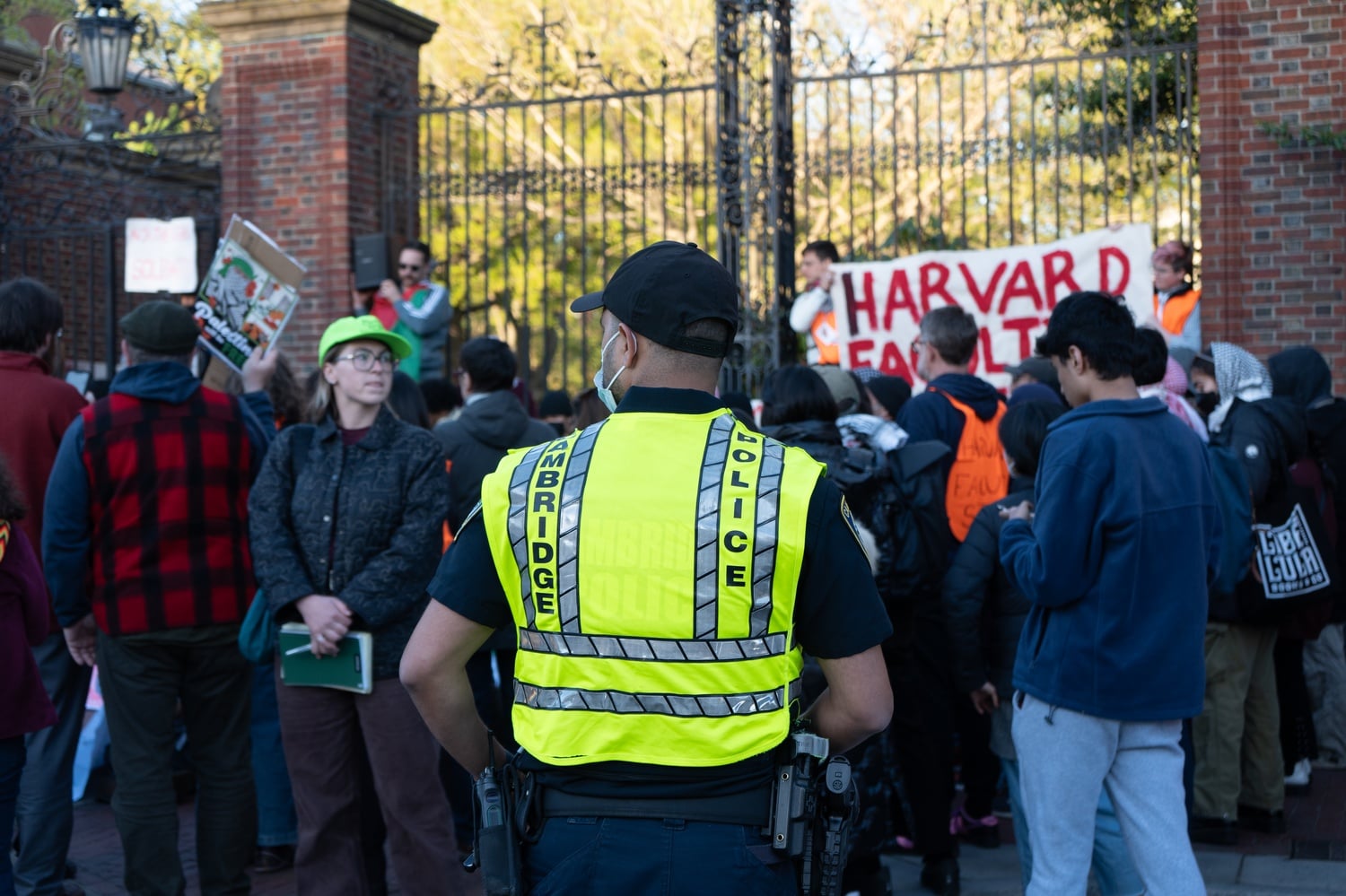 A Cambridge Police Department officer observes pro-Palestine protesters stage a sit-in during a rally on Saturday outside Johnston Gate.