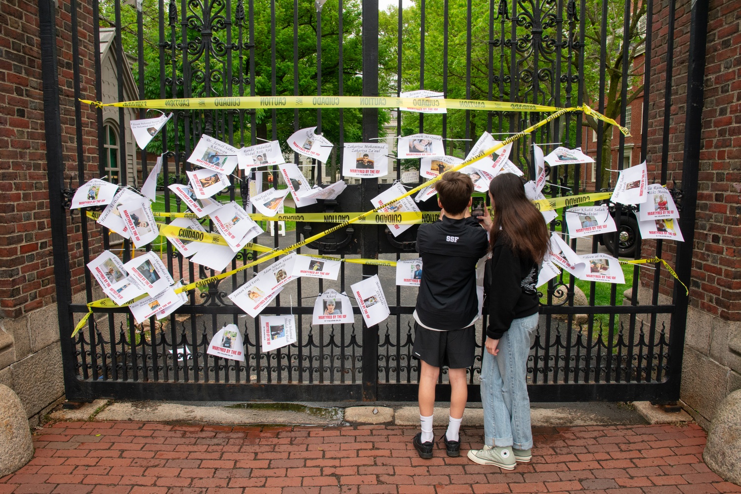 Protesters affix flyers bearing the names of Palestinians killed in the Israel-Hamas war to Johnston gate.