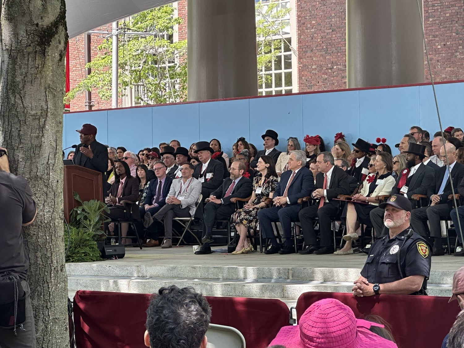 Interim Harvard President Alan M. Garber ’76 listens to award-winning actor Courtney B. Vance ’82 deliver the keynote speech at Harvard Alumni Day. Behind the podium, a stain is visible from the gold glitter attack against Garber from earlier in the ceremony.