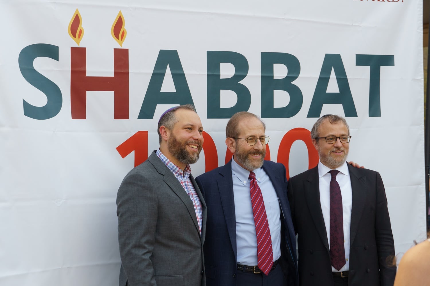 Harvard President Alan M. Garber '76 poses for a photo with two rabbis at last year's Shabbat 1000 in front of the Science Center.