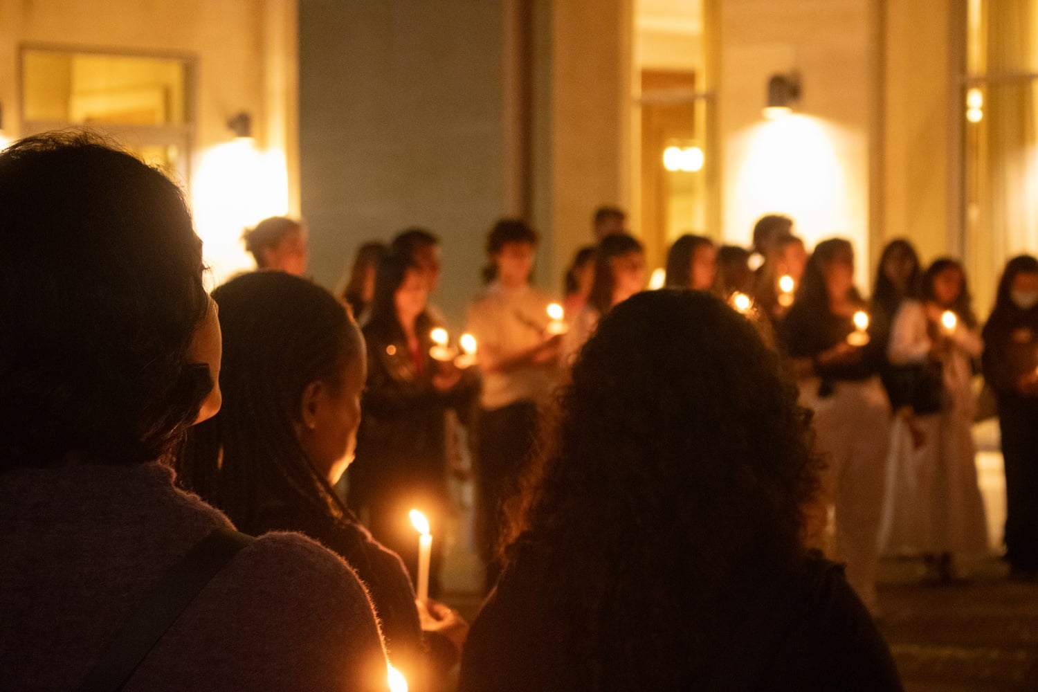 Protesters hold candles at a rally in front of Wasserstein Hall at the Harvard Law School on Monday evening.