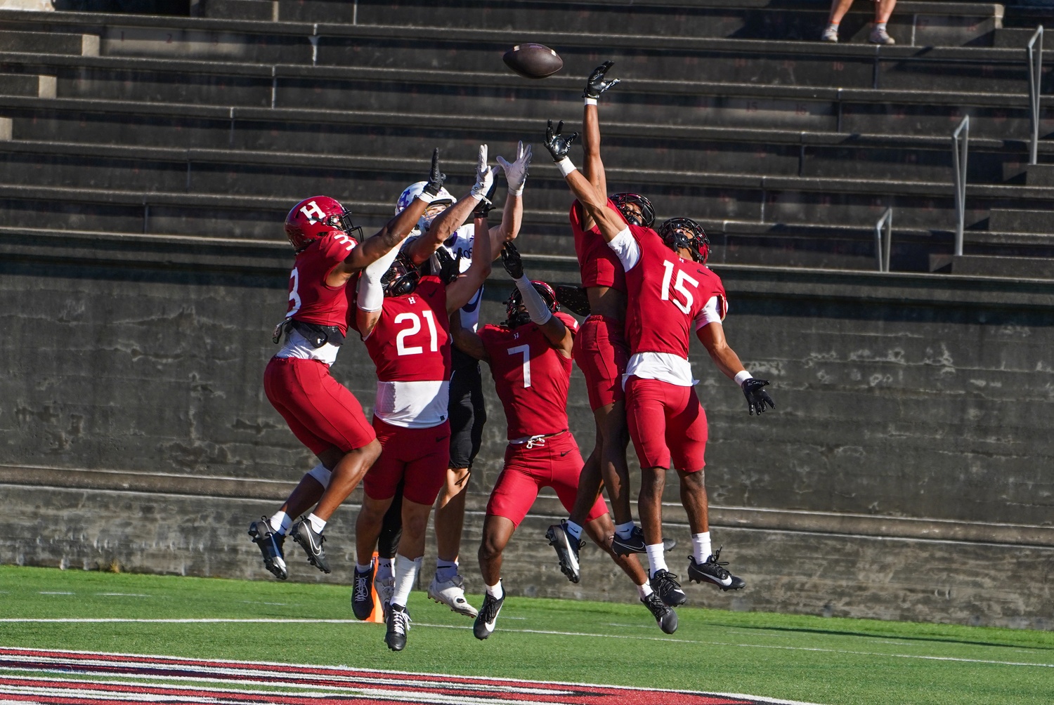 Harvard defenders try to prevent a Holy Cross receiver from hauling in a touchdown pass.