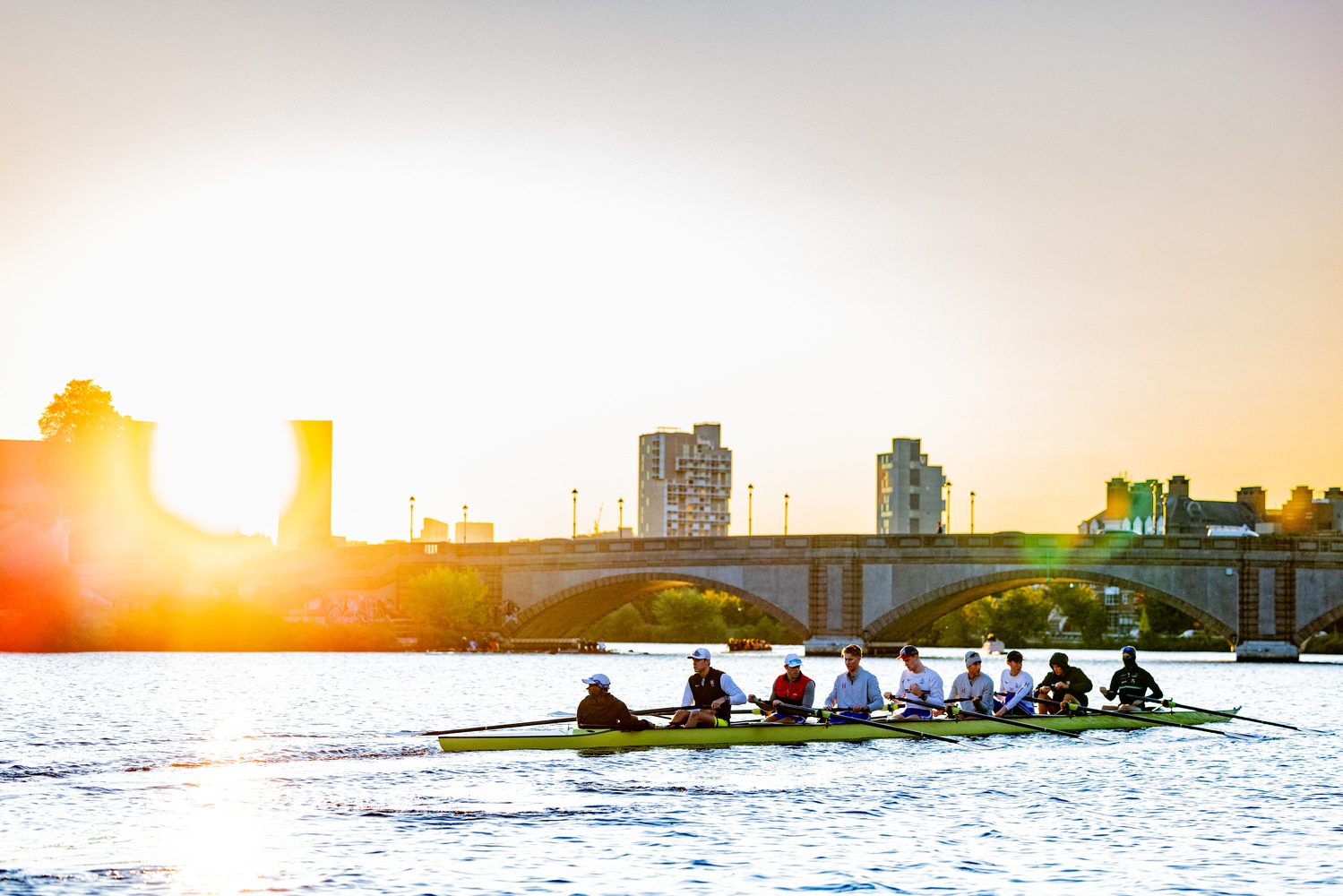 The Harvard men's crew team rows on the Charles as the sun rises.