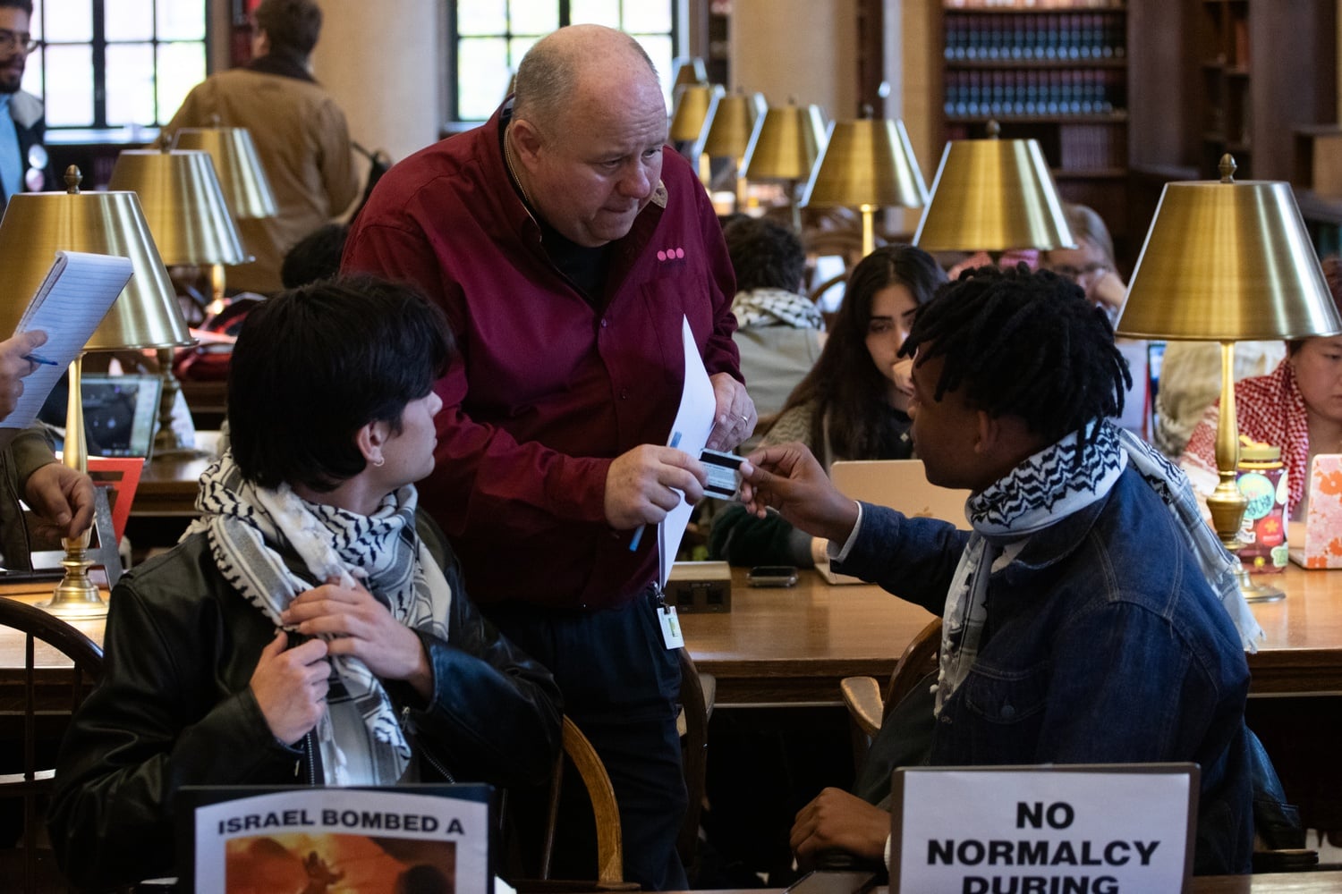 A security guard checked a student's HUID to write down their ID number at a Widener study-in on Tuesday.