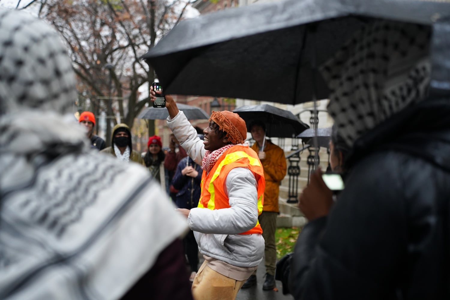 Harvard undergraduate student, Kojo Acheampong '26, is surrounded by fellow protestors as he jumps in chant during a Thursday afternoon walkout held by HOOP.