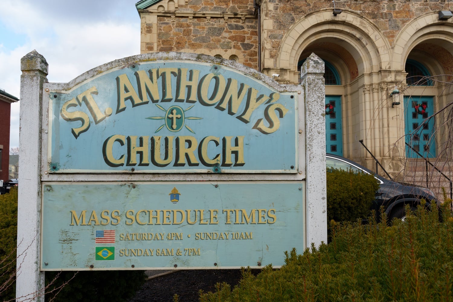 Uma placa exibe os horários das missas em inglês e português na Paróquia de Santo Antônio, na Holton Street, em Allston.