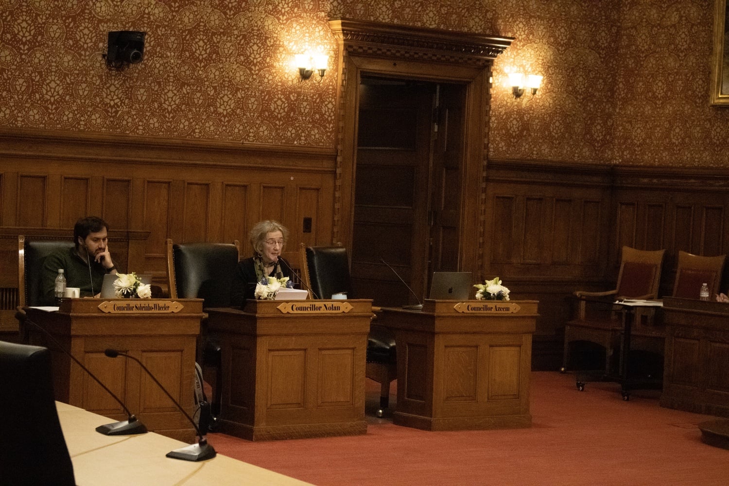 Cambridge City Councilors Patty M. Nolan ’80 and Jivan Sobrinho-Wheeler sit in Sullivan Chamber during the March 3 City Council meeting.