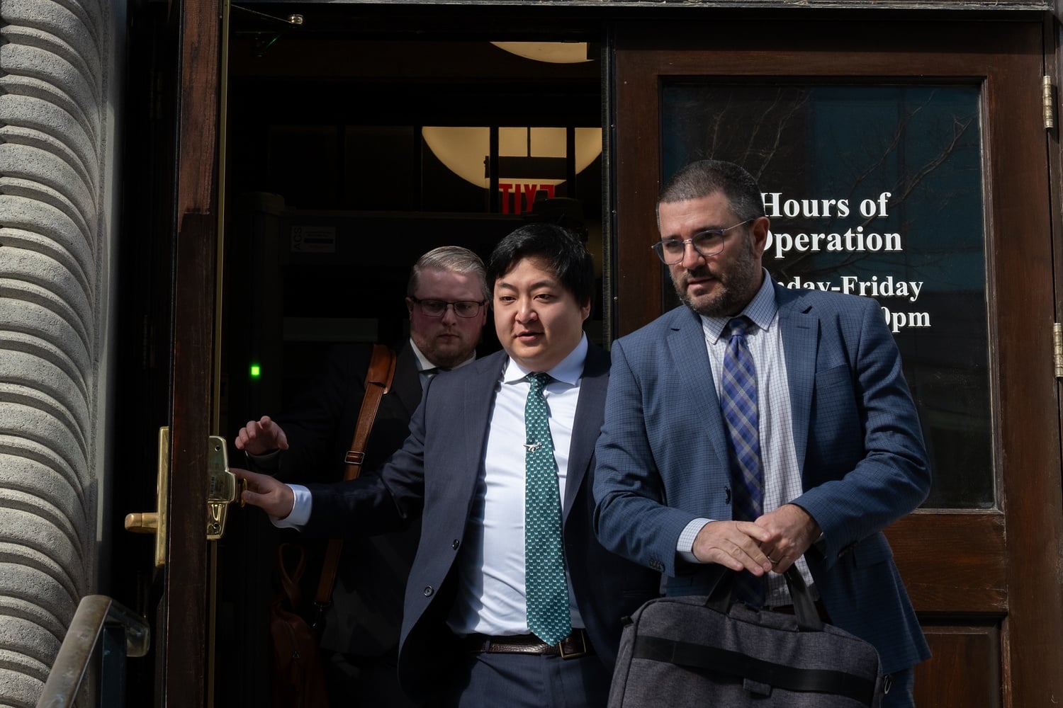 Mark Zhu (center), one of two defendants present at Friday’s hearing, exited the courthouse with lawyer Steven C. Goldwyn (right) after being criminally charged. Zhu’s arraignment is scheduled for May 9.