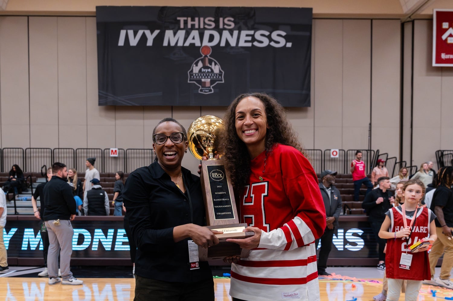 Claudine Gay and Carrie Moore hold the Ivy Championship trophy. Gay attended the final game against the Lions Saturday.