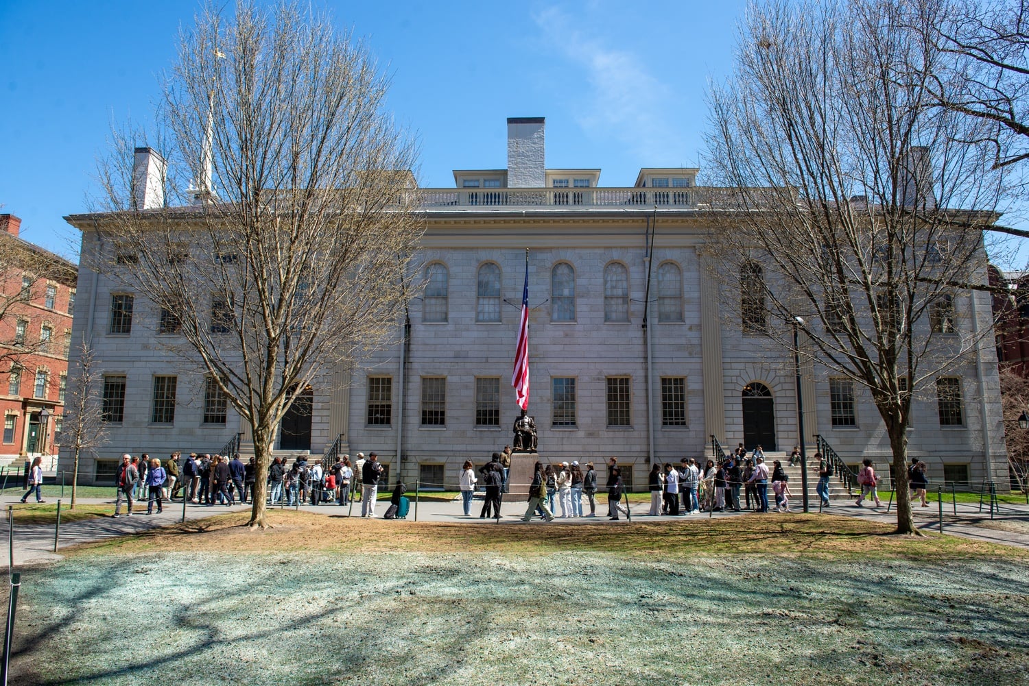 The American flag flies from University Hall over the John Harvard statue.