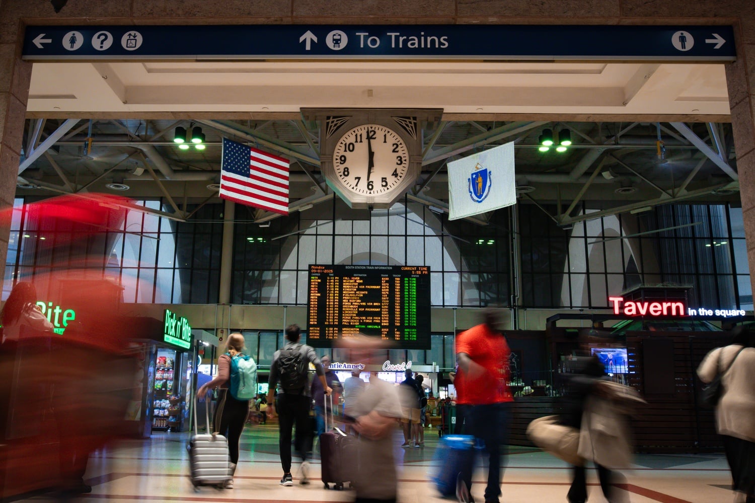 An American flag hangs opposite of a Massachusetts flag inside South Station.
