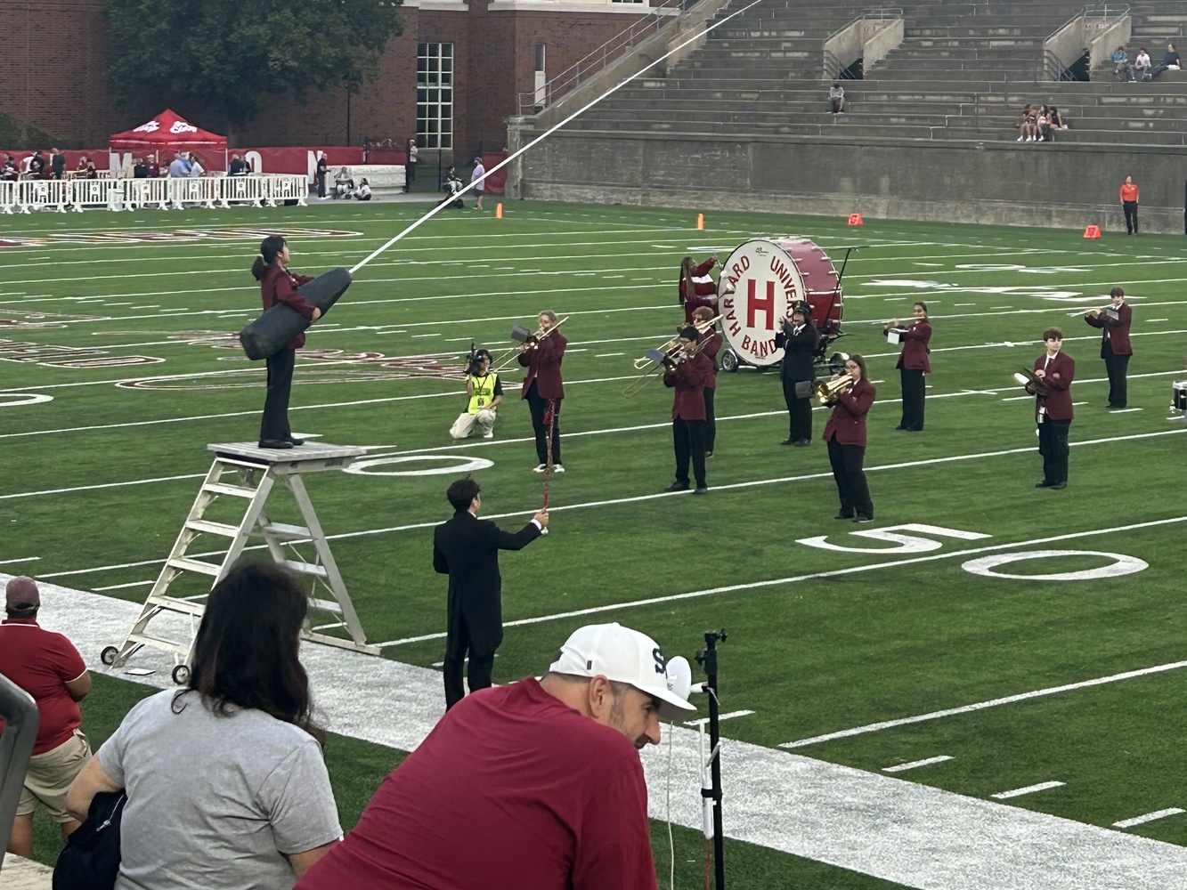 The Harvard University Band's student conductor Mei Fujimura '27 uses the band's 20-foot baton, which the Band unveiled at Harvard's game against Brown.