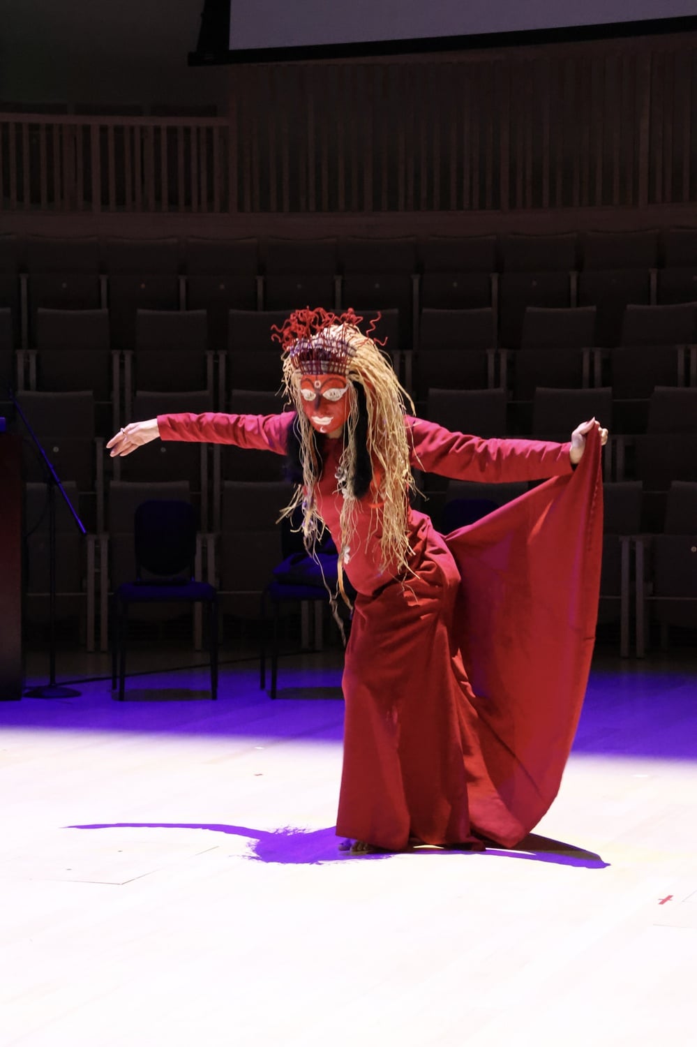Mesma Belsare, in a red dress with a red mask.