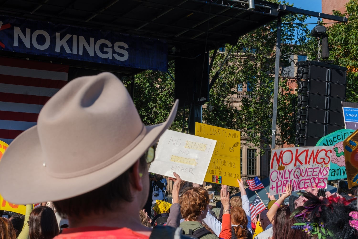 Protesters chant and hold up signs in front of the stage between speakers.