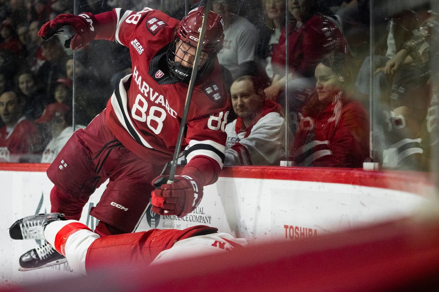 Freshman forward Aidan Lane hits a Cornell player along the boards during the physical second game of the series.