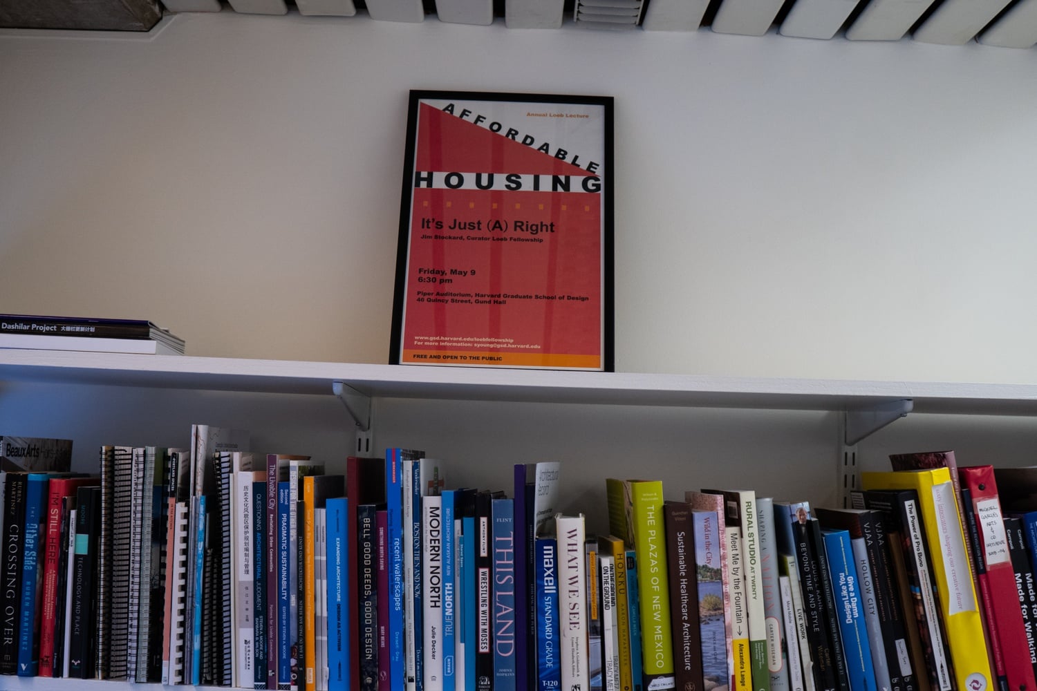 On top of Jim Stockard's bookshelf is a framed poster from a lecture he gave in 2014: “Affordable Housing, It’s Just (A) Right.”