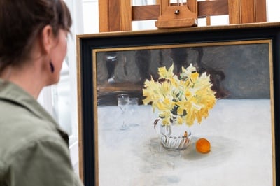 Cover image for Allison K. Jackson examines a painting and its frame.