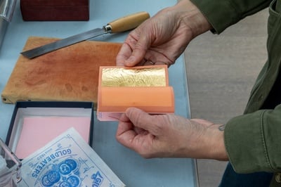 Cover image for Allison K. Jackson working with gold leaf for frame restoration.