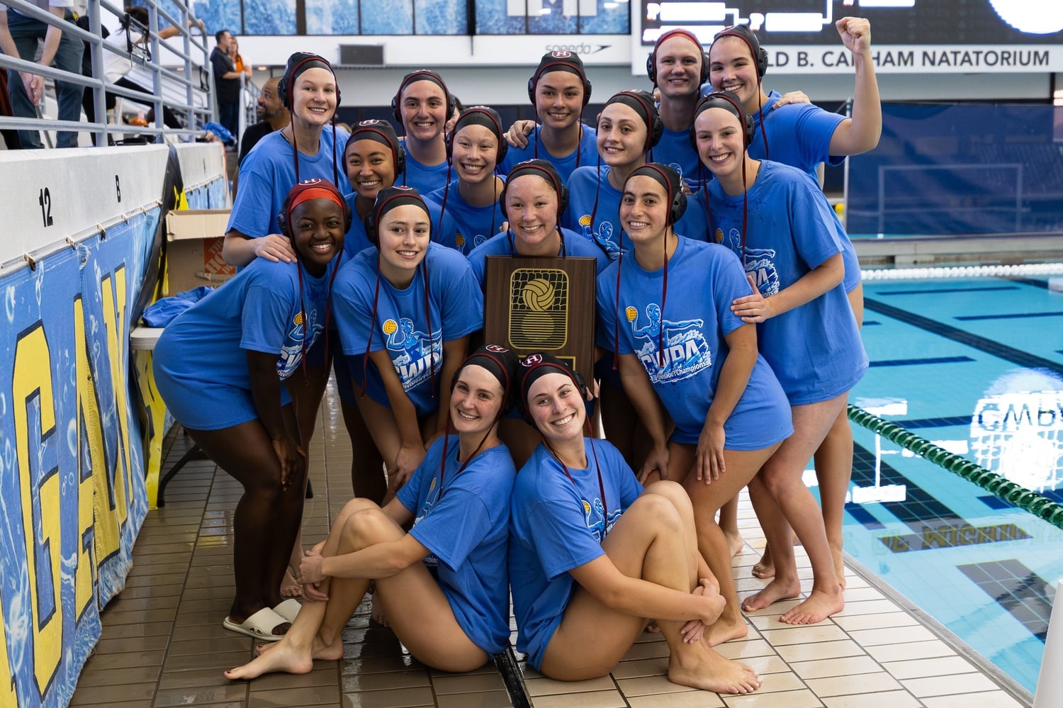 The Harvard women's water polo team poses with the CWPA Championship Plaque after a marathon 8-7 victory over Princeton.
