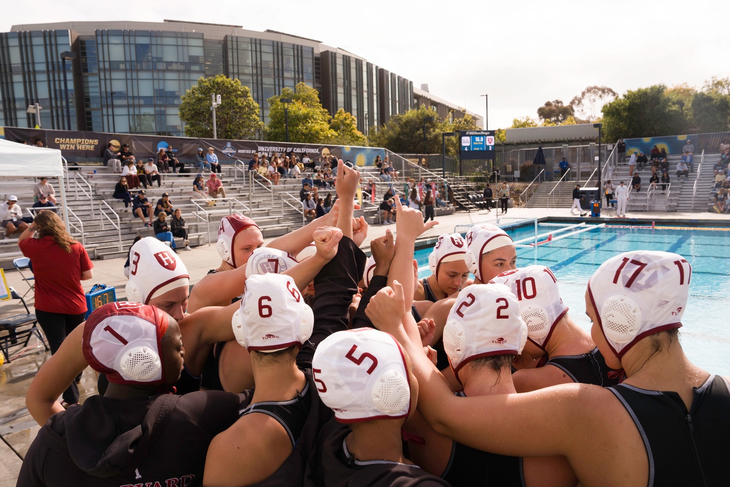 The Harvard women's water polo team huddles outside the pool as they take on the UCLA Bruins in the NCAA Quarterfinals