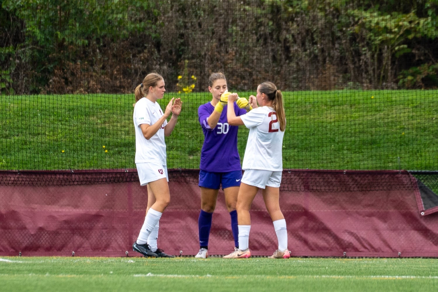 Harvard's defensive unit, including senior defender Amy König, sophomore goalkeeper Nicole Bidun, and senior midfielder Anya Van Den Einde, celebrates the shutout over the University of Connecticut Huskies. 