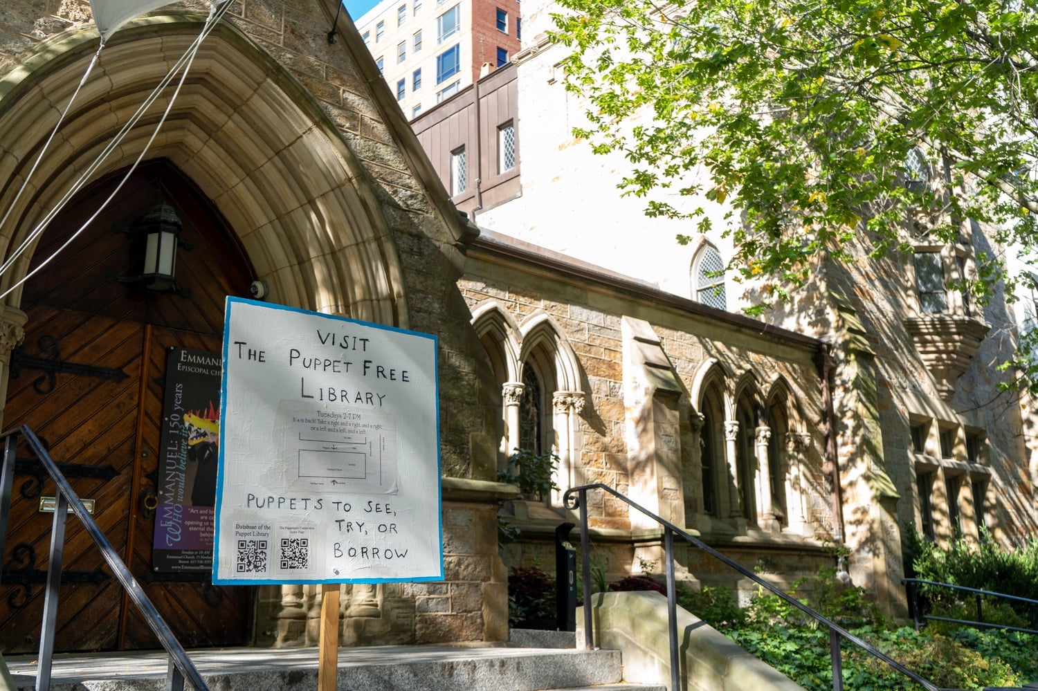 A sign in front of Emmanuel Church directs people towards the Puppet Free Library. The library is open on Tuesdays from 2 to 7 p.m.