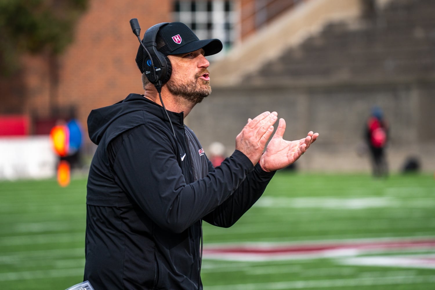 Head coach Andrew Aurich claps on the sidelines as Harvard defeats Holy Cross.